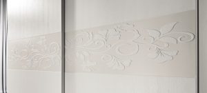 Collezione Armadi_modello Artemide Frassino Bianco a due ante in legno_dettaglio fascia centrale con decoro floreale in bassorilievo